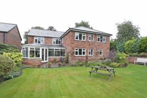 a large brick house with a picnic table in the yard at The Hinton Guest House in Knutsford
