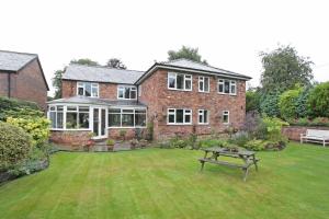 una gran casa de ladrillo con una mesa de picnic en el patio en The Hinton Guest House, en Knutsford