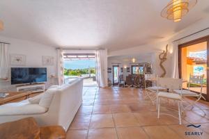 a living room with a white couch and a tv at Villa Il Varo - By Searly in Liscia di Vacca