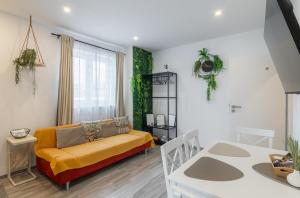 a living room with a yellow couch and a table at GreenSide ThermenSuite Frauenkirchen in Frauenkirchen