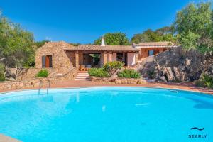 a house with a large swimming pool in front of a house at Villa San Teodoro - By Searly in Punta Molara