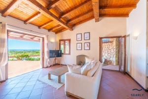 a living room with a couch and a tv at Villa San Teodoro - By Searly in Punta Molara