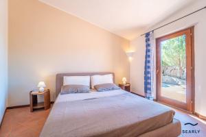 a bedroom with a bed and a large window at Villa San Teodoro - By Searly in Punta Molara +152 photos