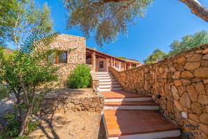 a stone house with stairs and a stone wall at Villa San Teodoro - By Searly in Punta Molara