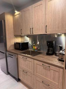 Una cocina con armarios de madera, fregadero y microondas. en Elfs Retreat close to Santa Claus Village, en Rovaniemi 8 fotos más