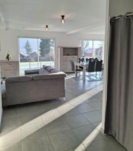 ein Wohnzimmer mit einer Couch und einem Tisch mit Stühlen in der Unterkunft La Marceline, maison proche du village in Charavines