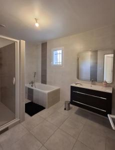 ein großes Badezimmer mit Badewanne und Waschbecken in der Unterkunft La Marceline, maison proche du village in Charavines