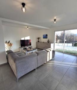 ein Wohnzimmer mit Sofa und Fernseher in der Unterkunft La Marceline, maison proche du village in Charavines