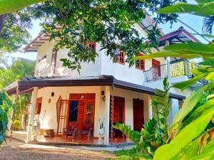 ein weißes Haus mit roten Türen und Bäumen in der Unterkunft Yala EAGLE NEST & Safari in Tissamaharama