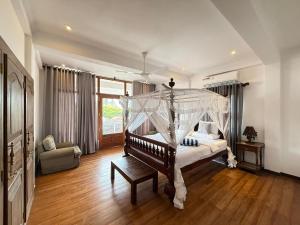 a bedroom with a bed with a canopy at Margaret House in Mirissa