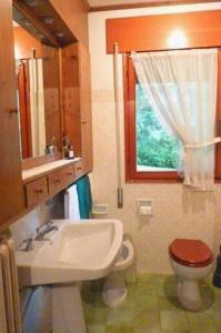 een badkamer met een wastafel en een toilet en een raam bij Ca' Donatella - Mountain View Terrace & Parking in Cortina dʼAmpezzo