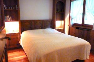 een slaapkamer met een wit bed en een raam bij Ca' Donatella - Mountain View Terrace & Parking in Cortina dʼAmpezzo