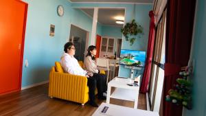 two men sitting on a couch in a living room at 佐世保まち宿 in Sasebo