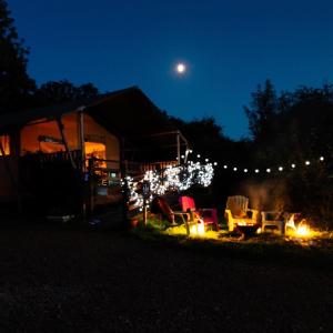 a backyard with lights and chairs and a fire at Leafy Fields Glamping in Ashill