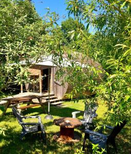" village tonneaux de tirpoil " في Montilliers: طاولة وكراسي أمام كابينة