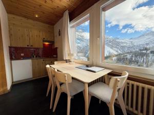 a kitchen with a table and chairs and a large window at Miraflor Sonja by Arosa Holiday in Arosa