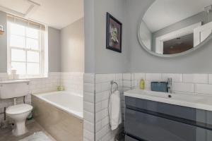 a bathroom with a tub and a toilet and a mirror at Kincaple Garden Flat - Kincaple in Guard Bridge +24 photos
