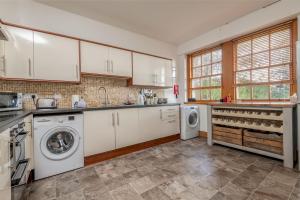 a kitchen with white cabinets and a washer and dryer at Kincaple Garden Flat - Kincaple in Guard Bridge