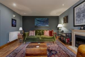 a living room with a green couch and a fireplace at Kincaple Garden Flat - Kincaple in Guard Bridge