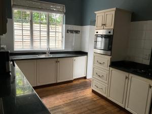 una cucina con mobili bianchi, un lavello e un microonde di Casablanca Guest House a Durban