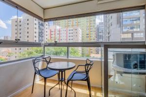 a balcony with two chairs and a table in front of a window at Handy Paraíso condomínio com piscina ao lado do Ibirapuera in Sao Paulo