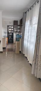 a living room with curtains and a kitchen at Mytlestayresidence in Kisii