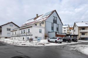 a large white house with cars parked in the snow at Auszeit Schwarzwald in Breg