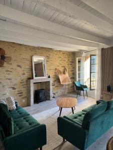 L'écrin au Coeur du Village في روشفور-أون-تير: غرفة معيشة بها كنبتين خضراء وموقد