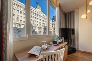 a room with a desk and a large window at Hyatt Centric Gran Via Madrid in Madrid
