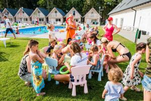 a group of people sitting in chairs by a pool at Holiday Park & Resort Pobierowo - całodniowe animacje i podgrzewany basen w cenie in Pobierowo