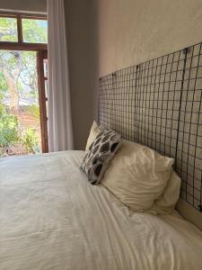 ein Bett mit zwei Kissen und einem Fenster in der Unterkunft Cozy Ensuite Borrowdale in Harare + 5 Fotos