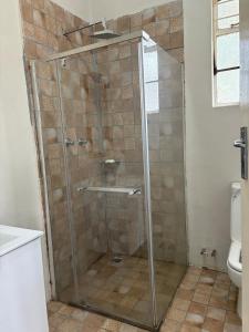 eine Dusche mit Glastür im Badezimmer in der Unterkunft Cozy Ensuite Borrowdale in Harare