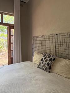 ein Bett mit zwei Kissen und einem Fenster in der Unterkunft Cozy Ensuite Borrowdale in Harare