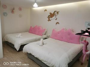 a bedroom with two beds with pink pillows and a horse wall at Hotel O ZZZ in Kuah