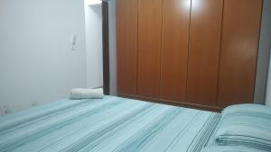 a bedroom with a bed and a wooden closet at 2 Qts próx Vila Militar, Sulacap e Campo dos Afonsos in Rio de Janeiro