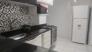 a kitchen with a sink and a stove and a refrigerator at 2 Qts próx Vila Militar, Sulacap e Campo dos Afonsos in Rio de Janeiro