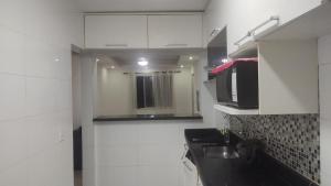 a white kitchen with a sink and a microwave at 2 Qts próx Vila Militar, Sulacap e Campo dos Afonsos in Rio de Janeiro +11 photos