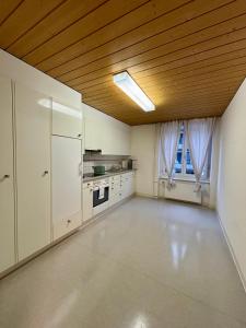 a large kitchen with white cabinets and a wooden ceiling at Zurich Essentials Simple Apartment in Zürich