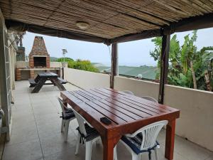 Una mesa y sillas de madera en un balcón con una parrilla en 48 Cintsa Bay, en Cintsa West