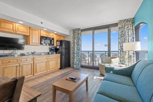 een woonkamer met een blauwe bank en een keuken bij Beach Cove Resort Unit 625 Corner Condo with Direct Oceanfront Balcony in Myrtle Beach