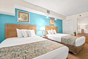 twee bedden in een hotelkamer met blauwe muren bij Beach Cove Resort Unit 625 Corner Condo with Direct Oceanfront Balcony in Myrtle Beach