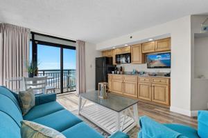un salon avec un canapé bleu et une cuisine dans l'établissement Beach Cove Resort Unit 1106 - End Condo with Direct Oceanfront Balcony, à Myrtle Beach