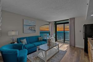 un salon avec un canapé bleu et une télévision dans l'établissement Beach Cove Resort Unit 1106 - End Condo with Direct Oceanfront Balcony, à Myrtle Beach