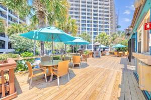 une terrasse avec une table, des chaises et un parasol dans l'établissement Beach Cove Resort Unit 1106 - End Condo with Direct Oceanfront Balcony, à Myrtle Beach