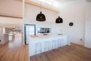 a kitchen with white walls and a counter with stools at Oceana - A Panoramic Beachfront Escape for Groups in Port Elliot