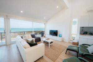 a living room with a white couch and a television at Oceana - A Panoramic Beachfront Escape for Groups in Port Elliot