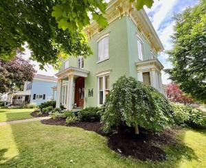 a green house with a tree in the yard at Wisteria Suite -The Belvedere Inn in Oswego