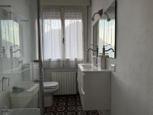 a white bathroom with a toilet and a sink at Le Vetrate sul Lago Lake Como Amazing View in Nesso