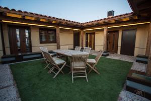 un patio con mesa y sillas en el césped en Apartamentos Turísticos La Panadería de Flora, en Martiherrero