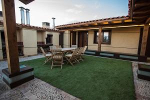 un patio con mesa y sillas en el césped en Apartamentos Turísticos La Panadería de Flora, en Martiherrero